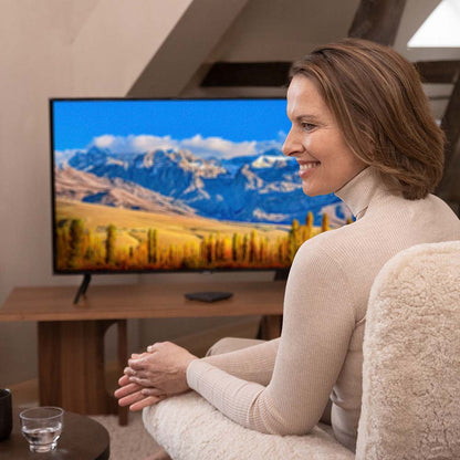 Widex TV Play 2 accessory for Allure and Moment Sheer hearing aids, showing the device connected to a TV in a living room setting.